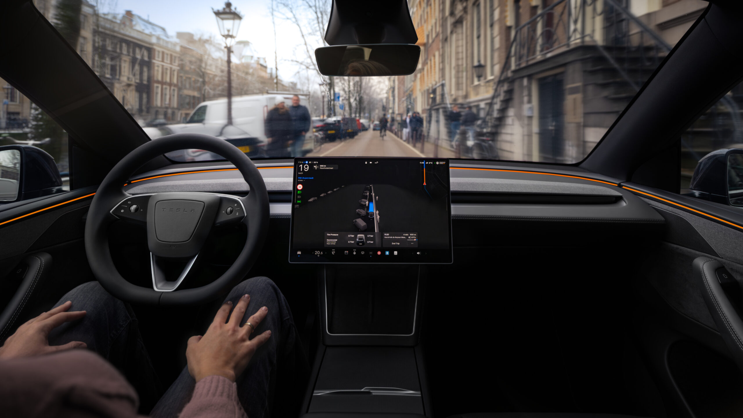 Filholderassistenten i Tesla krever snart abonnement 1 Førerplass i en Tesla med skjerm som viser en levende 3D-fremstilling av trafikken rundt bilen. Føreren har begge hender i fanget mens bilen kjører gjennom en gate i Amsterdam med syklister og fotgjengere.