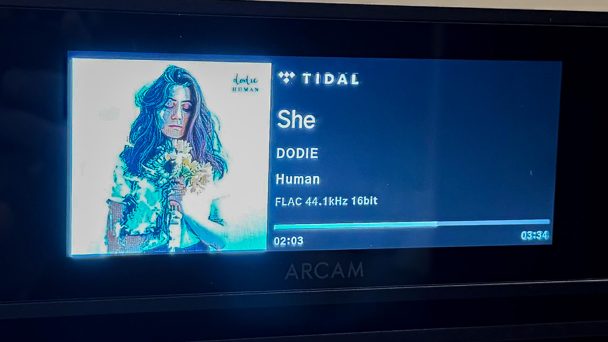 Arcam SA35 2 Skjermen på Arcam SA35 viser plateomslag og låtinfo fra Tidal: «She» av Dodie i FLAC 44,1 kHz/16 bit.