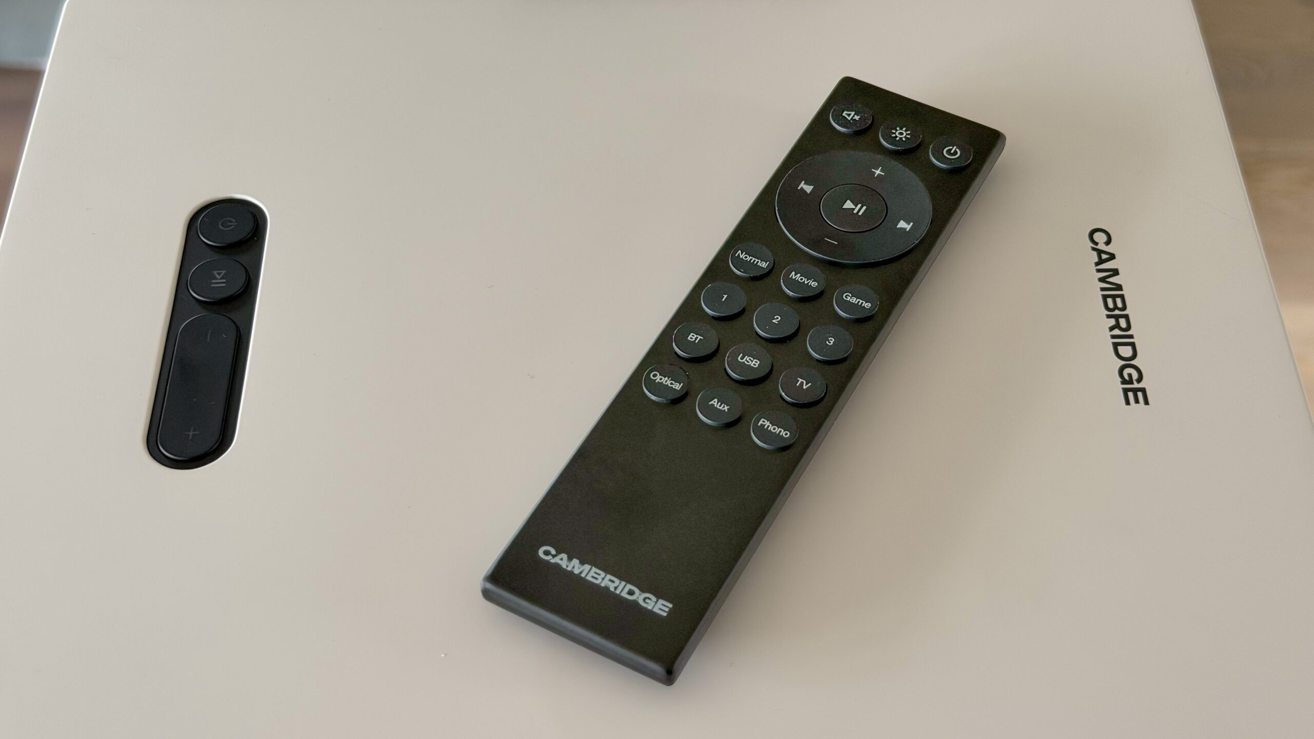 Cambridge Audio L/R X 6 Bluetooth-fjernkontrollen og en separat volumkontroll til Cambridge Audio L/R X på et bord.