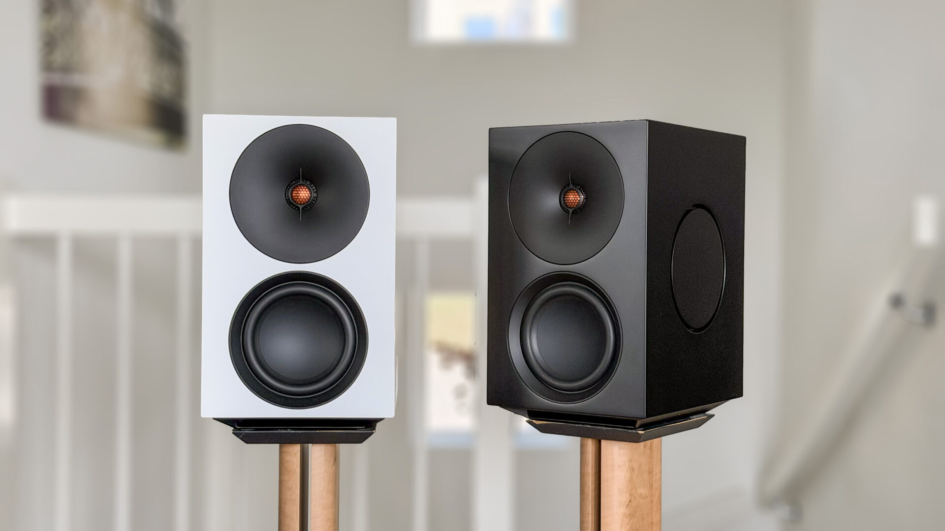 Cambridge Audio L/R X 3 Cambridge Audio L/R X i hvit og svart utførelse på trebeinsstativer i en lys stue, sett forfra.